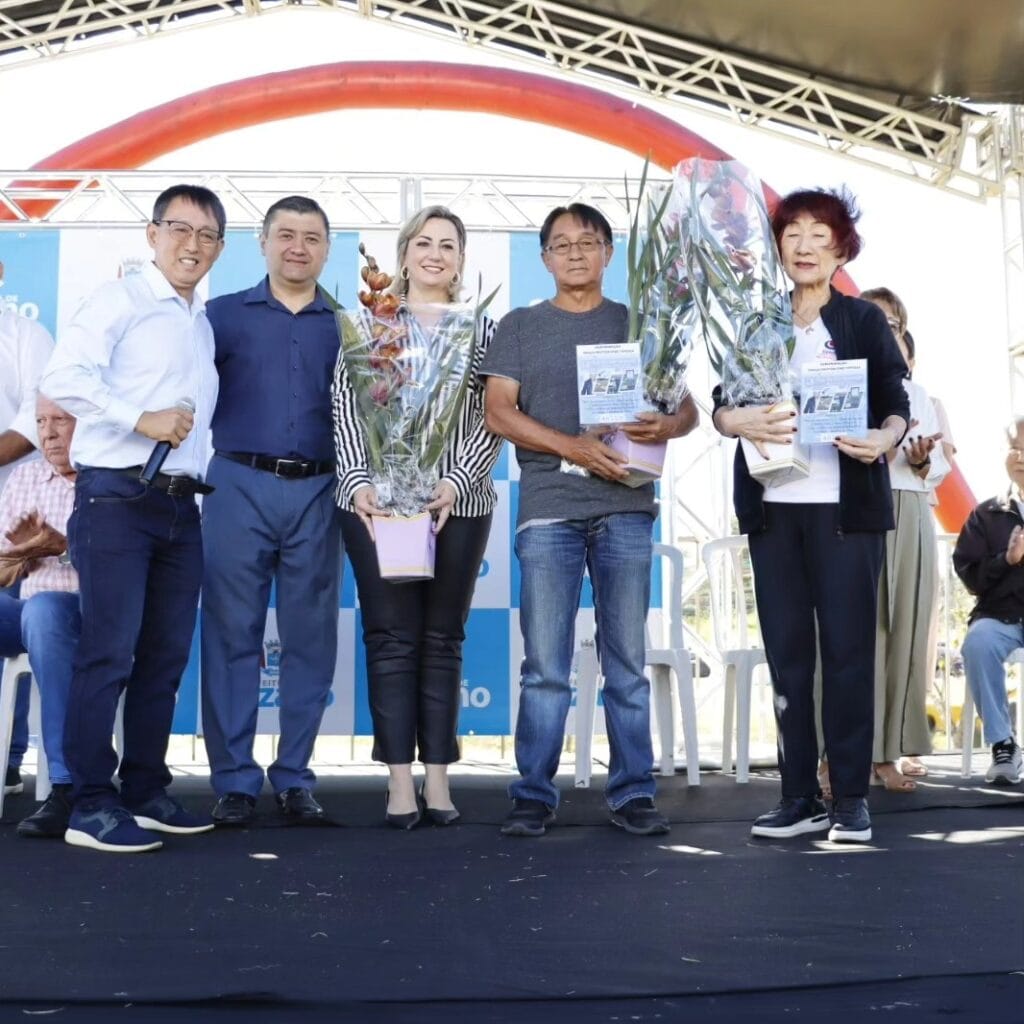Praça Sol Nascente é reinaugurada com homenagem a Junji Toyoda Espaço passou por revitalização, incluindo limpeza, pintura e paisagismo; entrega ocorreu na manhã desta sexta-feira (19/04) A Prefeitura de Suzano reinaugurou na manhã desta sexta-feira (19/04) a “Praça do Sol Nascente Doutor Junji Toyoda”, instalada na rotatória da rodovia Índio Tibiriçá (SP-31) com a avenida Governador Mário Covas Júnior, a Marginal do Una, e a rua José Sanches Marin. Em uma solenidade emocionante que reuniu autoridades municipais e familiares do homenageado, o espaço, que enaltece a presença nipônica na cidade, foi entregue totalmente revitalizado pela Secretaria de Manutenção e Serviços Urbanos e pelo Viveiro Municipal Tomoe Uemura, em parceria com a Associação Cultural Esportiva Agrícola Suzano (Aceas Nikkey) e com o Centro Educacional Nipo Brasileiro de Suzano (Cenibras). O local é simbólico para a cultura japonesa, fortemente presente em Suzano por conta de seus monumentos, e fica em um ponto de entrada para a região central da cidade. A revitalização contou com manutenção e pintura da escultura da artista plástica Tomie Ohtake, que foi instalada em 2008 no local em comemoração ao Centenário da Imigração Japonesa no Brasil; roçagem e capinação da grama; pintura da pista de caminhada e da ponte sobre o rio Una e reparos gerais, além de limpeza das demais estruturas. Todas as ações foram realizadas pela Secretaria Municipal de Manutenção e Serviços Urbanos. Além da obra de Tomie Ohtake, a praça conta com uma escultura do pássaro Tsuru, símbolo de saúde, boa sorte, felicidade, longevidade e fortuna, construída pelos artistas plásticos Lúcio e Rodrigo Bittencourt; e com um busto do ex-prefeito Pedro Sinkaku Miyahira, instalado em 2018 em comemoração aos 110 anos da Imigração Japonesa no Brasil. Nesta sexta, o espaço também recebeu duas árvores cerejeiras, plantadas pelas equipes do viveiro. O secretário Samuel Oliveira exaltou a colaboração do Viveiro Municipal para a revitalização da praça e se disse honrado por homenagear Junji Toyoda. “Essa cooperação entre as secretarias tem servido bem a população. Gostaria de agradecer a toda a equipe de manutenção que fez o trabalho de restauração, pintura e limpeza. Gratidão por esse momento. Me sinto muito honrado em estar nesta honraria concedida ao doutor Toyoda”, discursou o chefe da pasta. O filho do homenageado, Marcos Toyoda, agradeceu a iniciativa e exaltou o pai. “Ele foi um grande líder e ficamos muito felizes por lembrarem da trajetória dele. Muito obrigado”, disse aos presentes. O vereador e 3º secretário da Câmara de Suzano, Artur Takayama, ressaltou a forte ligação que possuía com o homenageado. “Falar do doutor Junji é difícil neste momento. Ele foi amigo, pescador, trabalhávamos juntos no Cenibras, ajudava a todos os departamentos. É uma pessoa que nos ensinava até dentro do barco, durante a pescaria. Tenho a certeza de que ele está vendo tudo isso aqui e está muito alegre”, declarou emocionado o parlamentar. Por fim, o prefeito Rodrigo Ashiuchi destacou a importância da cultura nipônica para a cidade, citou o ex-prefeito Pedro Miyahira e lembrou da colaboração que Toyoda deu para o município. “Esse é um dia muito especial em um local muito especial para nossa colônia japonesa. Aqui temos um busto do ex-prefeito Miyahira, com a frente voltada de forma proposital para a rodovia Índio Tibiriçá, em reconhecimento por tudo o que ele fez para nossa cidade. Esta praça tem esculturas, mas faltava um nome para ela, que a identificasse, e quando pensamos no doutor Junji Toyoda, tivemos a certeza de que não haveria pessoa mais indicada. Ele foi mais do que um dentista e colaborou muito para nossa cidade com seus 50 anos de profissão. Ele fez uma relação de amizade com as pessoas que estão aqui. Agradeço a família dele por permitir que falemos deste grande suzanense que muito orgulha nossa cidade”, discursou o chefe do Poder Executivo. Presenças A solenidade contou ainda com as presenças da primeira-dama e dirigente do Viveiro Municipal, Larissa Ashiuchi; dos secretários municipais Afrânio Evaristo (Gabinete e Segurança Cidadã); Alex Santos (Governo); Arnaldo Marin Junior, o Nardinho (Esporte e Lazer); e Marcelo Prado (Controladoria Geral); dos vereadores Pedro Ishi e Lazario Nazaré Pedro, o Lázaro de Jesus; do primeiro paciente do homenageado, Dener Brum; do presidente da Associação Nipo-Brasileira de Assistência Social (Enkyo), Kazuo Nakada; do presidente da Associação Cultural Suzanense (Bunkyo), Reinaldo Katsumata, do diretor Tadashi Watanabe e da presidente do Departamento de Gateball da associação, Adriana Kiota; do presidente da Aceas Nikkey, Carlos Hiraoka, e da vice-presidente da entidade, Yugi Yamagami; do presidente do Conselho Gestor do Cenibras, Julio Mayer, e da diretora da escola, Keiko Shimada; e do diretor de Agricultura da Secretaria de Desenvolvimento Econômico e Geração de Emprego de Suzano, Minoru Harada. Também prestigiaram o evento o diretor do Rotary Club de Suzano, Mario Egashira; o CEO do Suzano Vôlei, André Chiang; o presidente da empresa Senshi do Brasil, Fernando Brandão; o vice-presidente da Associação Comercial e Empresarial (ACE) de Suzano, Fernando Fernandes; o presidente da Associação Okinawa, Sérgio Yonamine; o gerente da Casa de Repouso Vila Ipelândia, Sérgio Mishima; e os amigos e pacientes do homenageado, Suami Azevedo e Cristiane Domschke. Familiares do homenageado também estiveram no local, dentre eles a esposa Yasuko Mitsudo Toyoda, os filhos Marcos, Daniela e Fabiana Toyoda, as netas Pietra, Mariah, Letícia e Júlia, o neto Rafael, as irmãs Mieko Toyoda e Massaio Massuda, a nora Talita Teraoka e o cunhado Ossamu Murai. Trajetória Filho de Yoshiro Toyoda e Toshi Toyoda, Junji Toyoda nasceu em 8 de novembro de 1948, em Suzano, e se formou em Odontologia na Unicamp, em Piracicaba, juntamente com sua esposa. Ao longo da sua vida, também atuou em diversos projetos sociais. Em 1982 passou a integrar o Rotary Club de Suzano e, nos anos de 1988 e 1989, presidiu a entidade. Já em 1998 foi líder do intercâmbio de grupos de estudo, levando profissionais à província de Aichi, no Japão. Realizou um trabalho junto à Aceas e ao Cenibras. Estruturou uma biblioteca japonesa especial no local para valorização da cultura e, nos últimos anos, trabalhou para a implantação de campos de gateball, plantios de árvores frutíferas, hortas e plantas para o ensino das crianças, cultivo de peixes e até mesmo a criação de um mini zoológico. Junji Toyoda faleceu aos 74 anos, em dezembro de 2022, deixando os familiares e um importante legado de altruísmo, vitalidade e respeito ao próximo.